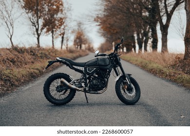 Scrambler motorcycle off-road machine, motorbike parked on a forest road with autumn trees and leaves - Powered by Shutterstock