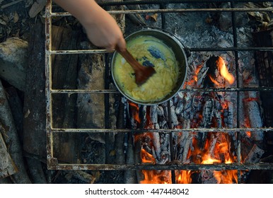 Scrambling Egg In A Cooking Pot On Firewood Stove. Cooking Using Firewood Is An Survival Skill Needed When Going To The Wilderness Or Outdoor Activity.