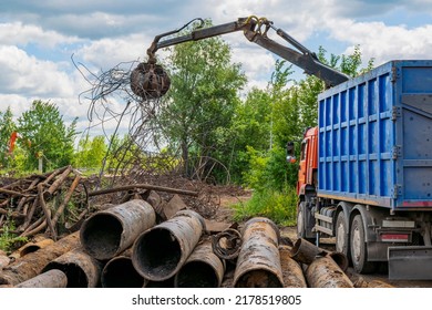 Scrap Metal Waste (steel And Cast Iron Pipes) Is Loaded Into Truck Using Hydraulic Manipulator With Grab.