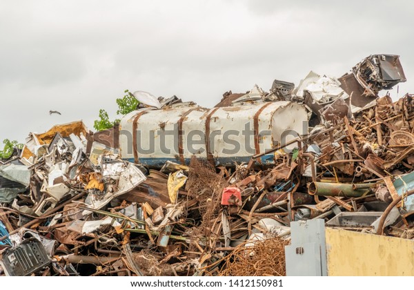 Scrap metal\
waste is stored in a recycling yard waiting to be melted down to\
manufacture new products. overcast\
weather