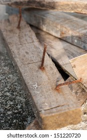 a scrap wood pile with protruding rusty nails