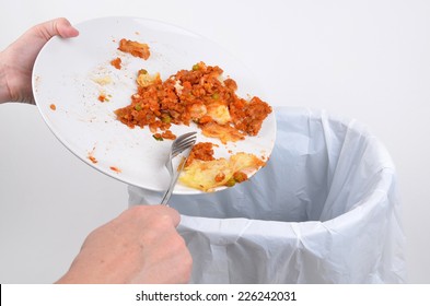 Scraping Food Waste From A Plate Into A Garbage Bin