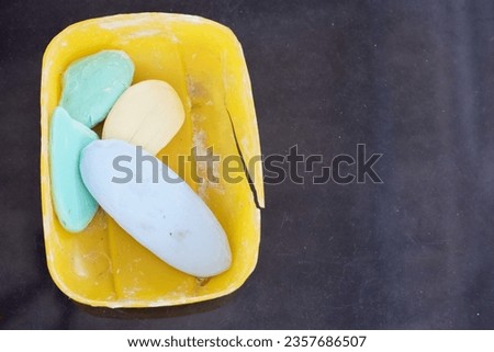 Scraps of leftover bar of soap in yellow box overlay on black background.
