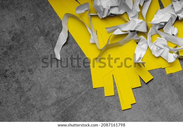 scraps of white crumpled paper and smooth yellow\
paper on a gray scuffed background; recycling of waste paper; the\
second life of paper