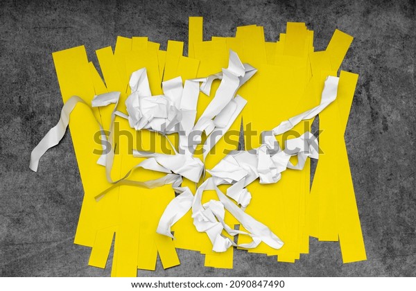scraps of white crumpled paper and smooth yellow\
paper on a gray scuffed background; recycling of waste paper; the\
second life of paper
