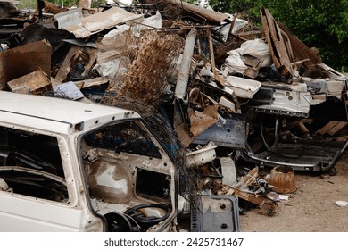 The scrapyard is a cluttered space filled with various scrap metal, old car parts, and other debris. It includes a white car door, a blue car door, and a rusty metal spring. - Powered by Shutterstock