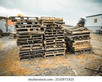 The scrapyard filled with a variety of wooden pallets, some intact, others broken. The weathered, rustic textures emphasize industrial decay, recycling, waste management, and upcycling potential - Powered by Shutterstock