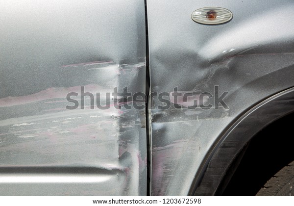 scratched\
car door and fender after an accident, close up car body damage\
scratches and blow in the side of the gray\
car.