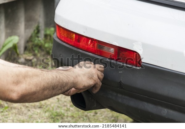 Scratched rear\
bumper on a white car, cracks and bumper repair close-up. White car\
with a broken and cracked\
bumper