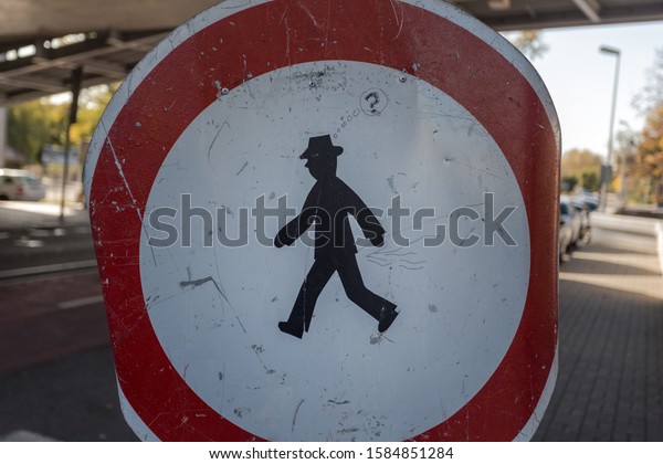 Scratched up street crossing sign with\
small man traversing in a small european\
country