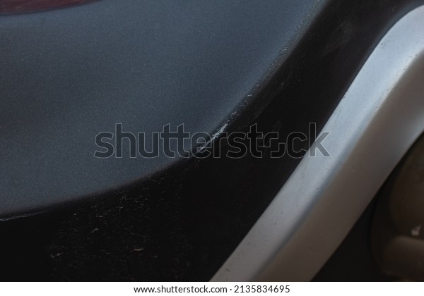 Scratches on the\
rear bumper of a black gray\
car.