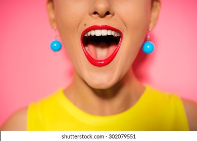 Scream And Shout! Close Up Of Opened Female Mouth. Bright Red Lips. Pink Background