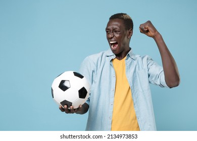 Screaming african american man football player in casual shirt yellow t-shirt isolated on blue background. Sport leisure concept. Playing football hold soccer ball expressive gesticulating with hands - Powered by Shutterstock