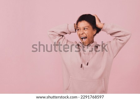 Screaming black girl keeping her hands on her head. Photo with copy space. Young emotional woman over pink background