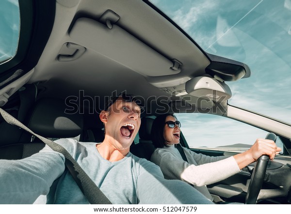 Screaming couple\
riding in car wide angle\
view