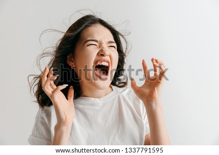 Screaming, hate, rage. Crying emotional angry asian woman screaming on gray studio background. Emotional, young face. Female half-length portrait. Human emotions, facial expression concept.