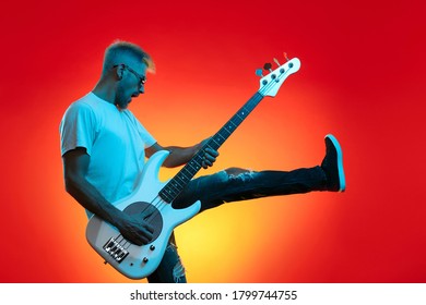 Screaming hipster man play white bass guitar in neon lights. Rock music concept - Powered by Shutterstock