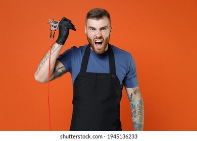 Screaming Professional Tattooer Master Artist Tattooed Man In Blue T-shirt Apron Hold Machine Black Ink In Jar, Equipment For Making Tattoo Art On Body Isolated On Brown Background Studio Portrait