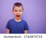 screaming six year old boy in a blue t-shirt on a purple background