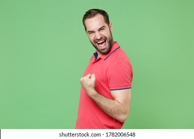 Screaming young bearded man guy in casual red pink t-shirt posing isolated on green background studio portrait. People sincere emotions lifestyle concept. Mock up copy space. Doing winner gesture
