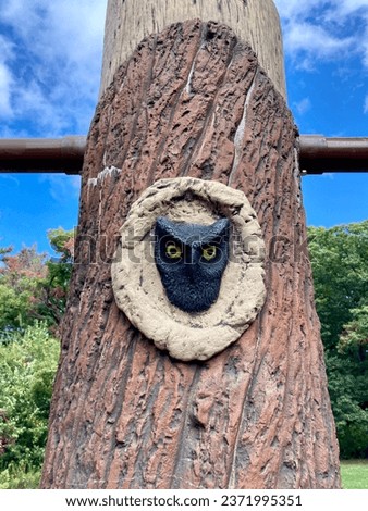 Screech Owl Looking out of Hole in Wooden Pole, Art at Public Playground in Whirlpool State Park, New York, Sky and Trees in Background