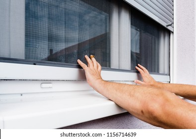 Screen on window. hands holds anti-insect mosquito net on pvc window