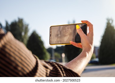 Screen View Of Young Woman With Yellow Painted Nails Taking Selfie At Golden Hour