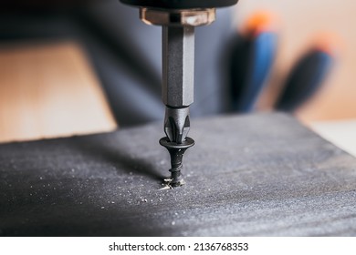 Screw Screwed Into Timber Wood On Wooden Top Table Background. Electric Screwdriver Or Drill Screwing Screw, Nail Or Bolt Into Wooden Planks. Repair Furniture, Carpenter Working.