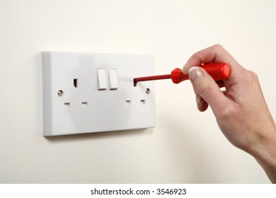 Screwdriver Being Pushed Into A UK Wall Socket