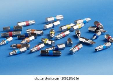 Screwdriver bits lying chaotically on the blue background. Copy space.