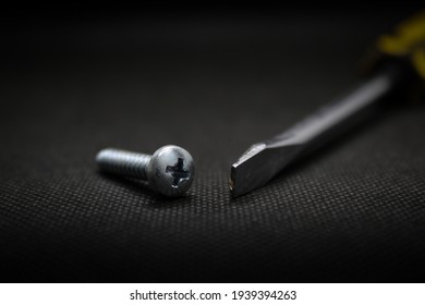 The screwdriver and the crosshead screw on a black background