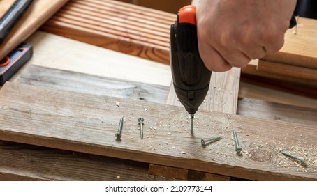 Screwdriver Electric Tool, Male Hand Screw On Wood.  Carpenter Work Bench Table Closeup View. DIY, Home Repair And Fix.