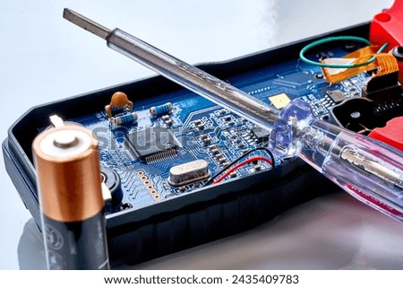 A screwdriver lies on a radio-electronic measuring device, a multimeter.                            