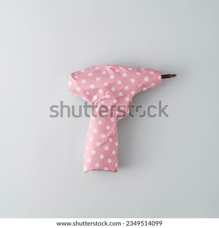 Screwdriver packed in pink gift paper with polka dots on blue background. Top view.  