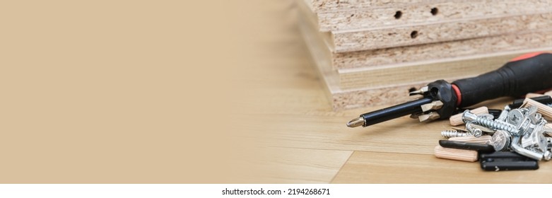 Screwdriver with removable nozzles and parts for assembling furniture on parts of cabinet furniture made of laminated chipboard background. Self-assembly of cabinet furniture. Banner, space for text - Shutterstock ID 2194268671