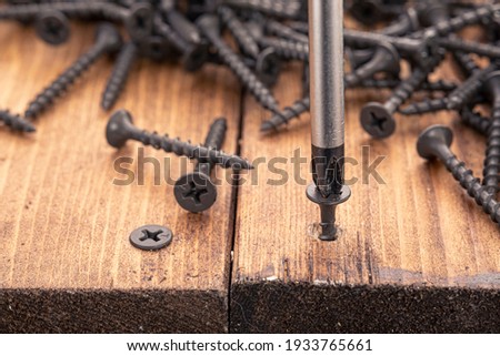 A screwdriver and screw on a wooden background. Screwdriver of Chromium Vanadium steel. Construction abstraction. Industrial background.