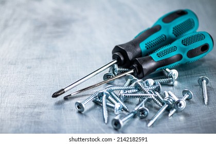 Screwdrivers with self-tapping screws on the table. On a gray background. High quality photo