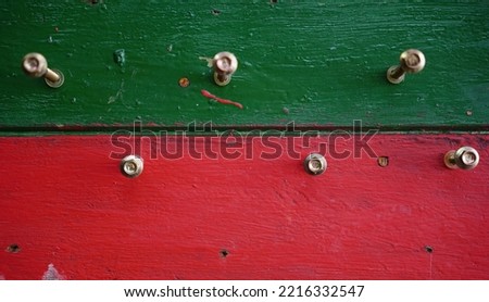 Screwers nailed on a red and green painted wood penal