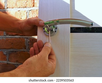 screwing bolts in the structure of the door handle on a light canvas by hand close-up, tightening the fasteners when installing the door mechanism with a hex key
