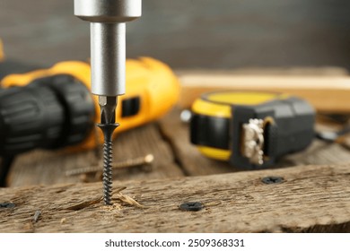 Screwing screw into wooden plank on table, closeup - Powered by Shutterstock