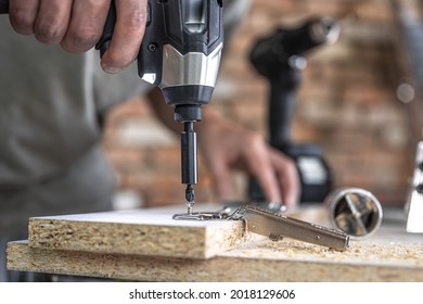 Screwing a self-tapping screw into a metal fastening hole on a wood strip using a screwdriver, the work of a carpenter.