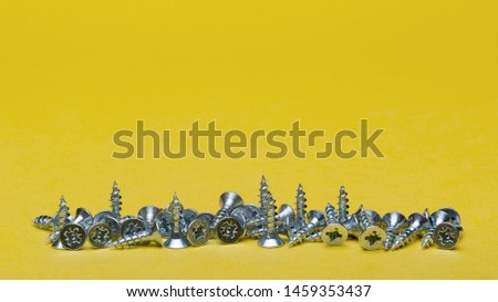 Screws on a yellow background. Close-up on screws. Screws as a background, wood screw.