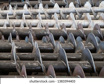 Screws For Screw Conveyors During Production. Carbon Steel Screws In The Foreground And Stainless Steel Screws In The Background.