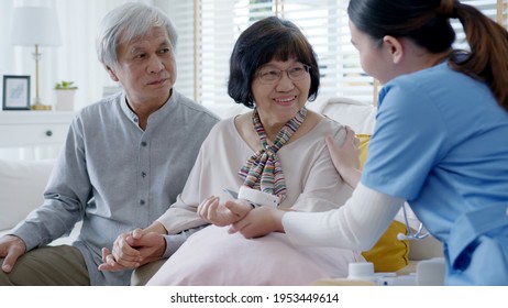 Scrub Nurse Doctor Using Digital Tonometer Check Blood Pressure For Old Asia Female At Home In Elderly Care Cardiovascular Medical Visit, Cholesterol Problem And Hospice Healthcare Caregiver Concept.