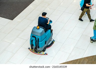 Scrubber-dryer Works In The Lobby Of The Shopping Center. The Process Of Cleaning Tiles In A Large Industrial Building. Top Down View. Unrecognizable Person