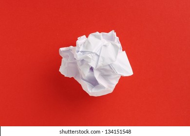 A Scrunched Up Ball Of White Printing Or Writing Paper In The Center Of A Red Paper Background