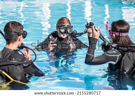 Scuba dive training in the pool with a smiling instructor teaching two students