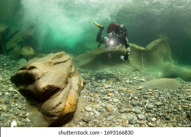 Scuba Diver Diving Cristal Clear River In Front Of Small Waterfall. Underwater World