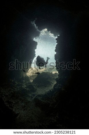 Scuba diver entering an under water cave - blackness surround the frame