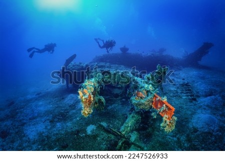 A scuba diver explores a sunken world war two fighter propeller airplane at the seabed of the Aegean Sea, Naxos island, Greece